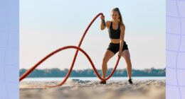 fit woman working out with battle ropes on the beach