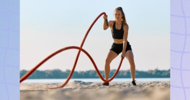 fit woman working out with battle ropes on the beach