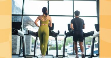 fit couple treadmill walking at the gym in front of windows