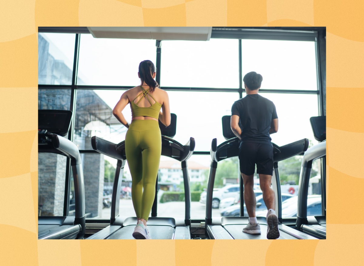 fit couple treadmill walking at the gym in front of windows