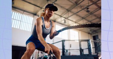 fit, determined blonde woman using battle ropes in boxing gym