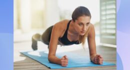 focused woman doing forearm plank on bright blue yoga mat in sunny room