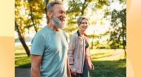 happy, mature couple walking outdoors for exercise on sunny day in park