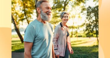 happy, mature couple walking outdoors for exercise on sunny day in park