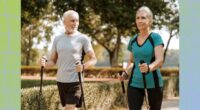 mature couple taking a brisk walk with walking poles along path in park on a sunny day