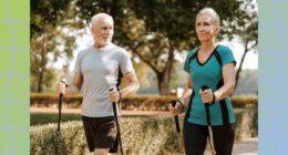 mature couple taking a brisk walk with walking poles along path in park on a sunny day