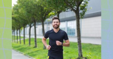 happy man power walking on tree-lined, paved path on sunny day