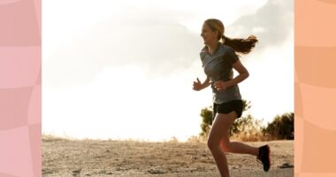 happy athletic woman running outdoors through mountain roads on overcast day