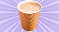 A frothy chai latte in a brown cup set against a vibrant violet background