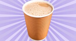 A frothy chai latte in a brown cup set against a vibrant violet background