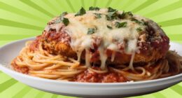 A plate of chicken parmesan over spaghetti set against a colorful background.