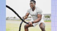 fit, muscular man doing battle rope workout in grassy field