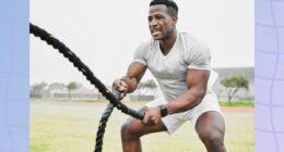 fit, muscular man doing battle rope workout in grassy field