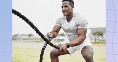 fit, muscular man doing battle rope workout in grassy field