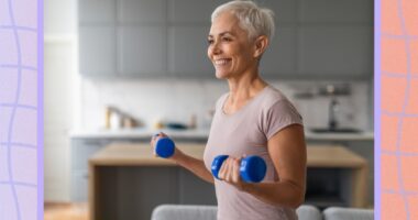 mature, happy woman lifting dumbbells in her living room