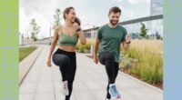 fit couple doing high knees exercise outdoors on paved walkway