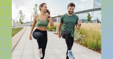 fit couple doing high knees exercise outdoors on paved walkway