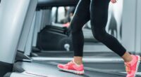 closeup woman walking on treadmill incline to speed up belly fat loss at gym during treadmill workout