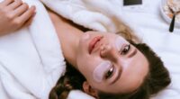 Young girl lies in bed early in the morning, next to a plate of oatmeal porridge, under the eyes of white patches.