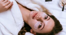 Young girl lies in bed early in the morning, next to a plate of oatmeal porridge, under the eyes of white patches.