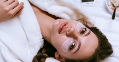 Young girl lies in bed early in the morning, next to a plate of oatmeal porridge, under the eyes of white patches.