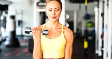 fit woman doing bicep curls demonstrating strength exercises for arm cellulite