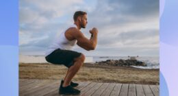 focused, muscular man doing squats on boardwalk leading out to beach on cloudy afternoon