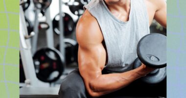 close-up of muscular man doing a seated bicep curl at the gym