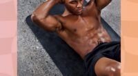 muscular-shirtless man with abs doing sit-ups on black yoga mat