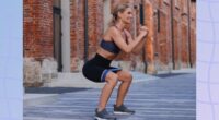 fit, middle-aged woman doing squats outdoors with a resistance band