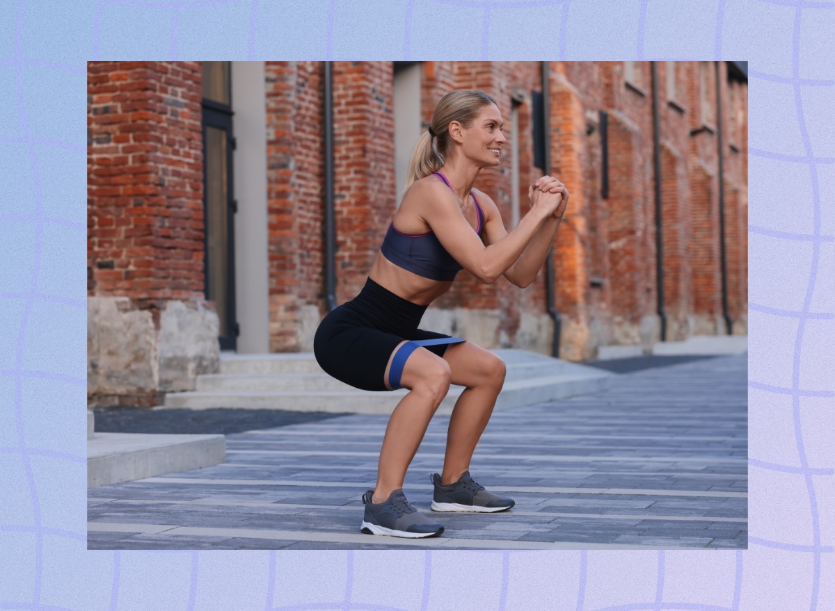 fit, middle-aged woman doing squats outdoors with a resistance band