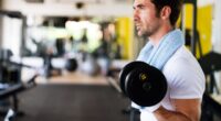 fit man doing bicep curls at the gym, close-up, concept of mistakes men make at the gym that hurt progress