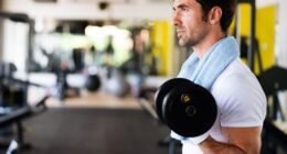 fit man doing bicep curls at the gym, close-up, concept of mistakes men make at the gym that hurt progress