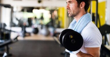 fit man doing bicep curls at the gym, close-up, concept of mistakes men make at the gym that hurt progress