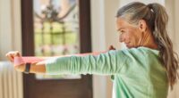 mature woman doing resistance band arm exercise at home, concept of weight-bearing exercises for adults over 50