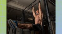 muscular, middle-aged shirtless man doing pull-up exercises in dark gym weight room