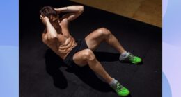 muscular man doing crunches on black workout mat