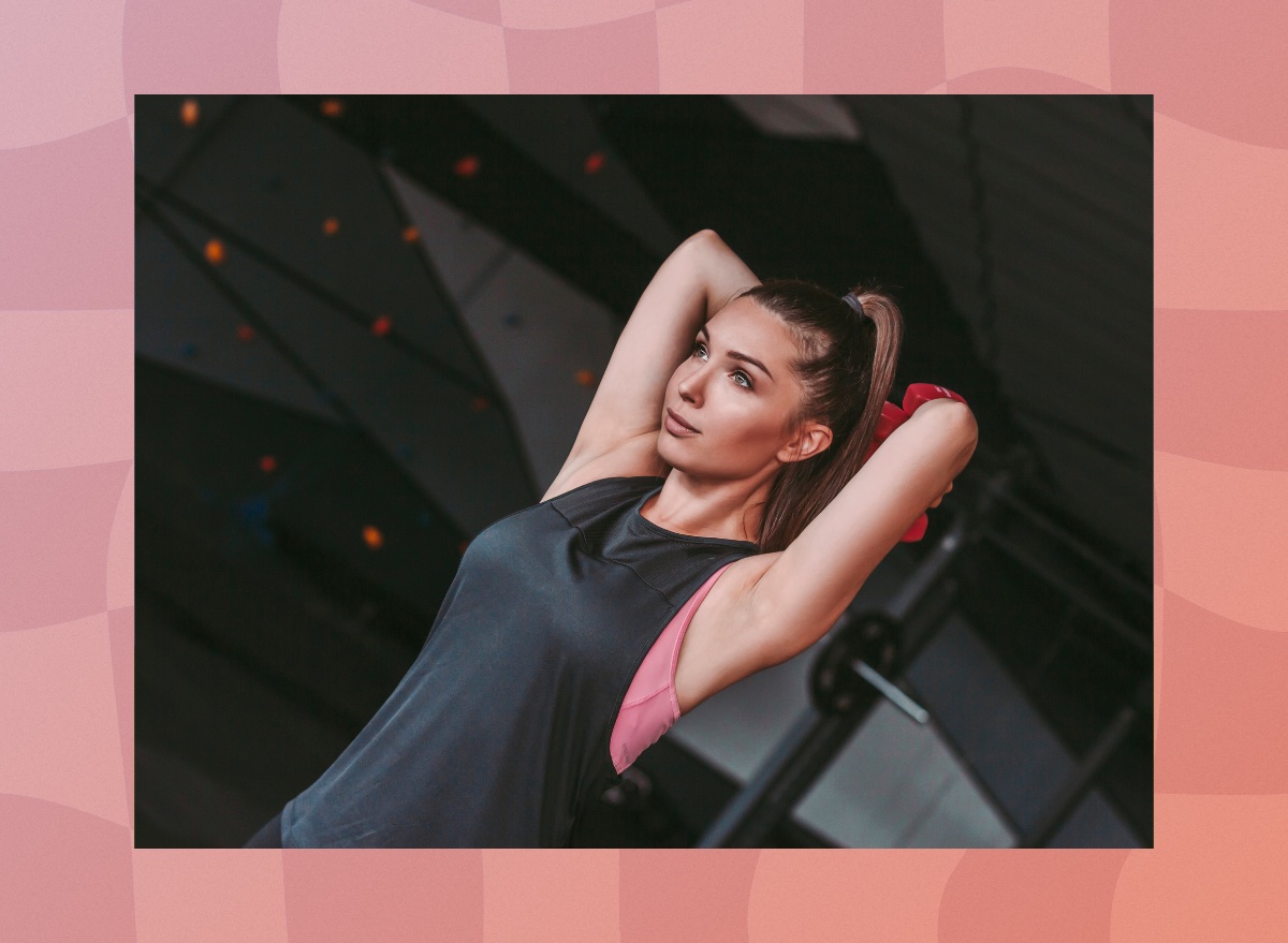 focused woman doing arm exercise with dumbbells in dark gym weight room