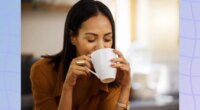 brunette woman drinking a hot beverage out of mug in bright kitchen