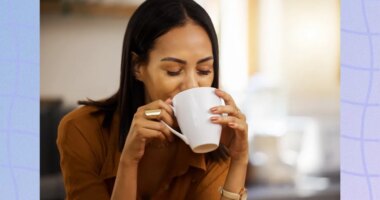 brunette woman drinking a hot beverage out of mug in bright kitchen