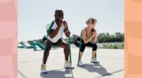 fit couple training with resistance bands outdoors on sunny day near a park