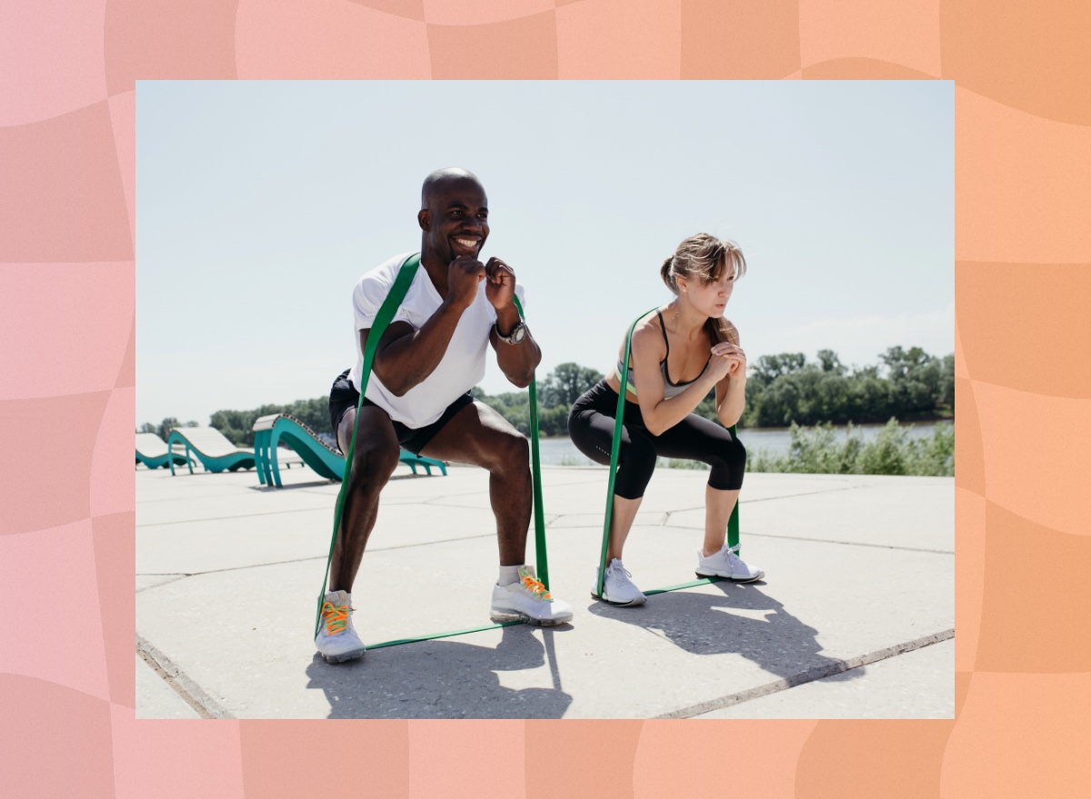 fit couple training with resistance bands outdoors on sunny day near a park