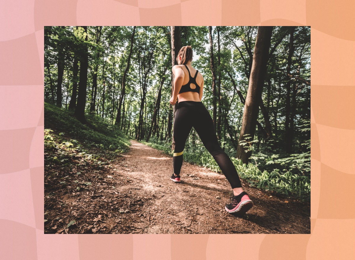 fit woman walking uphill on trail in the woods for exercise