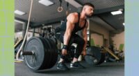 fit, muscular man doing a barbell deadlift with heavy weights at the gym