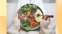 close-up of woman holding a healthy dinner plate filled with grains and vegetables