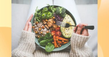 close-up of woman holding a healthy dinner plate filled with grains and vegetables