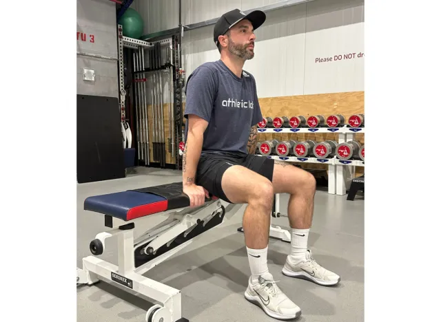 trainer setting up for a tricep dip on bench