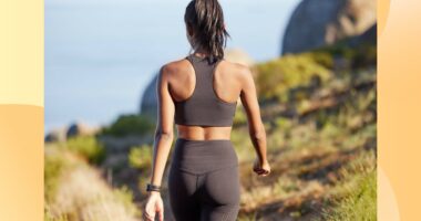 back view of fit brunette woman walking on a path by the ocean for exercise