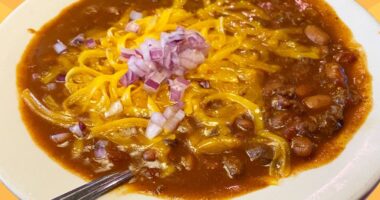 A bowl of chili from Texas Roadhouse set against a vibrant background