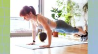 fit woman performing pushups in a bright living space next to floor to ceiling windows on bright sunny day